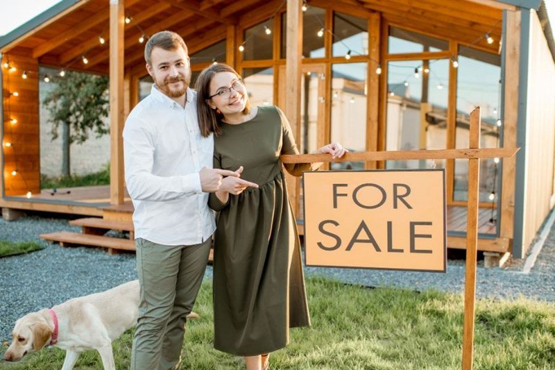 couple with for sale sign in front of home