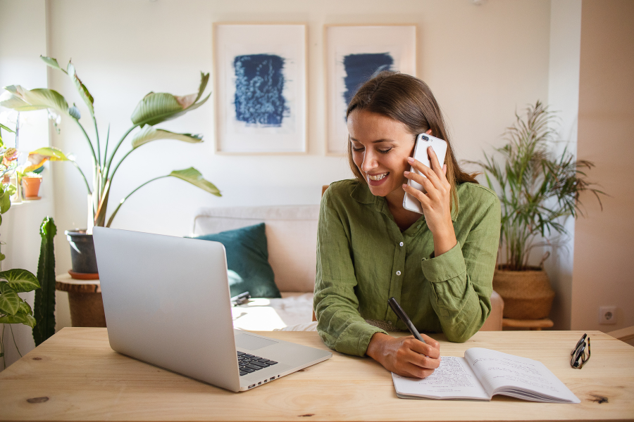 young woman on cellphone looking at laptop
