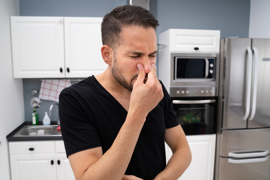 man standing in kitchen holding his nose