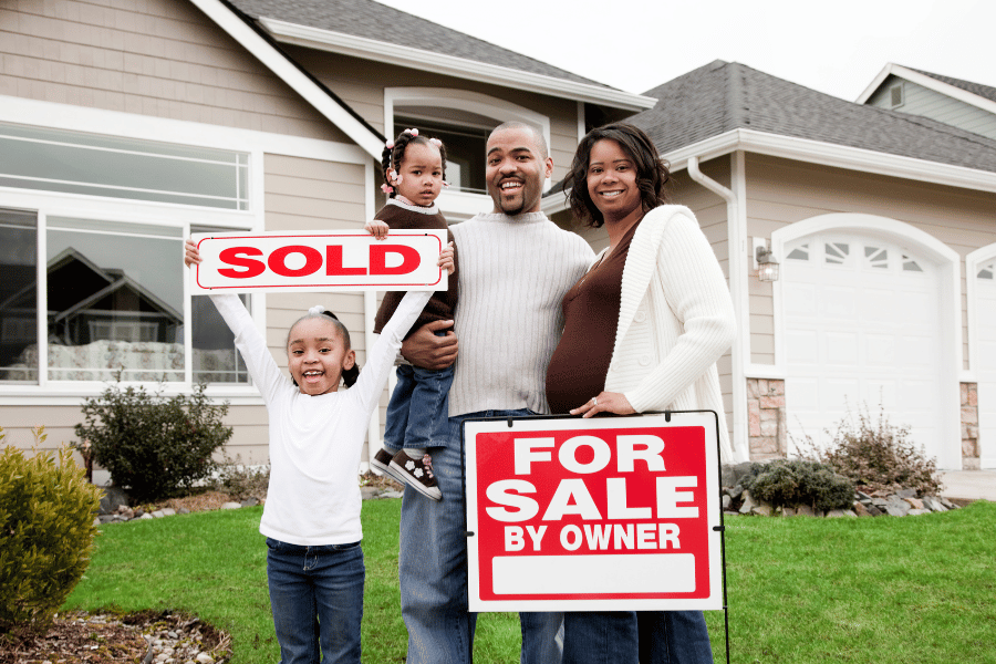 family of four holding a sale sign on a for sale by owner sign