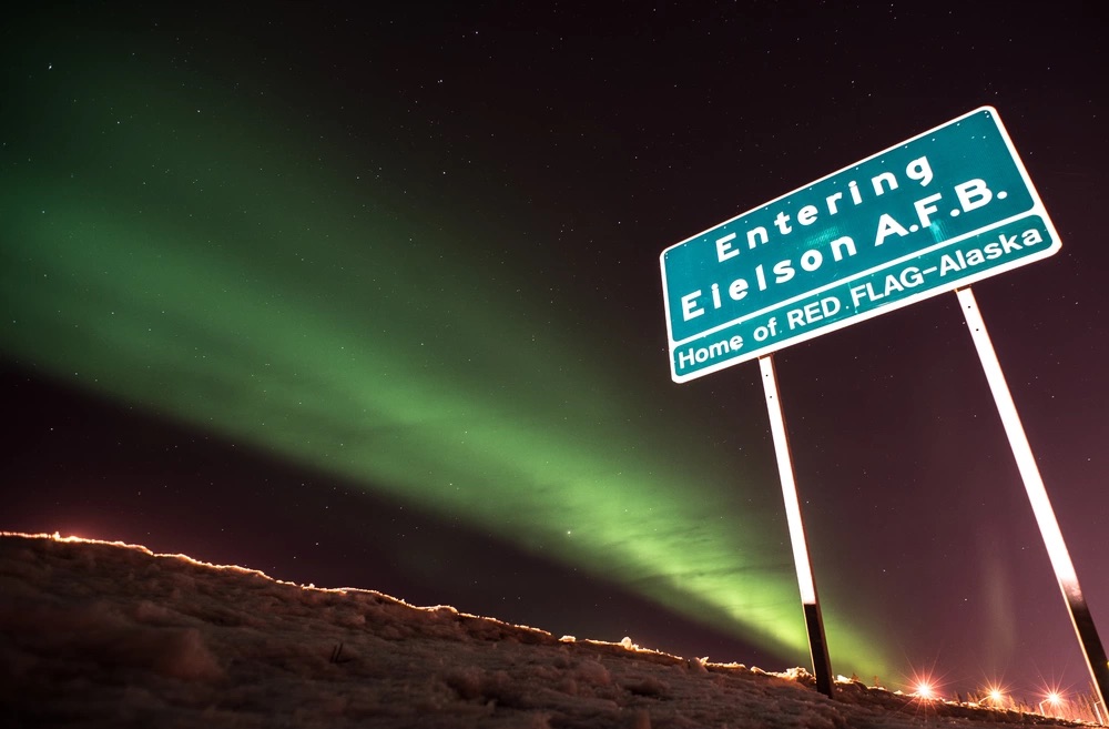 Northern lights green in sky with Eielson AFB alaska sign