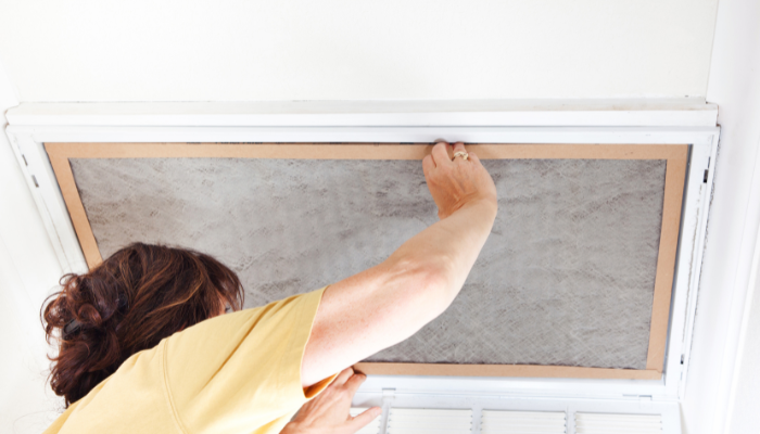 Woman changing dirty air filter in house.