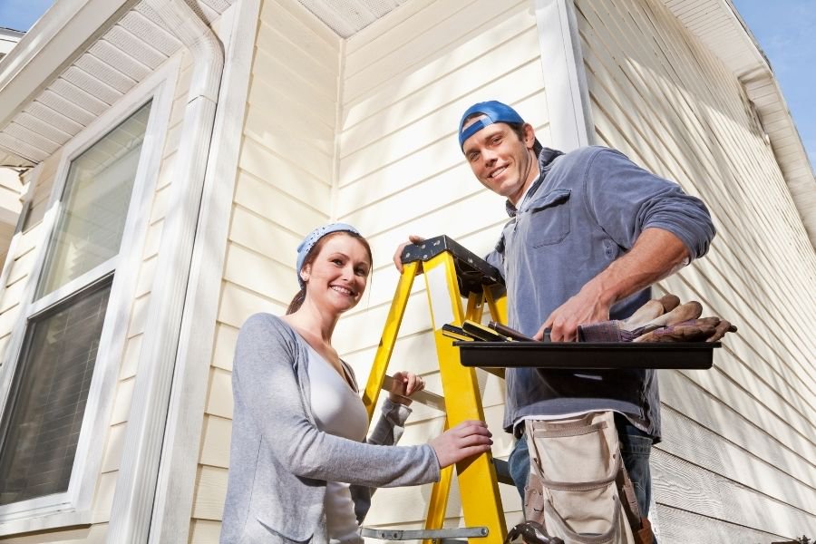 couple working on maintaining exterior of their home