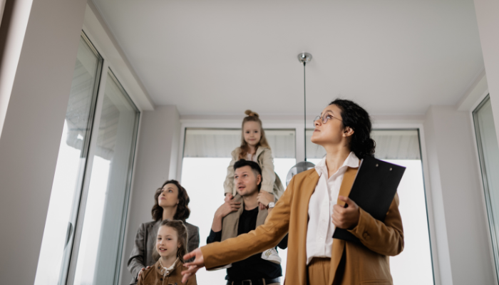 Photo of real estate agent showing a home's interior to a family of four.