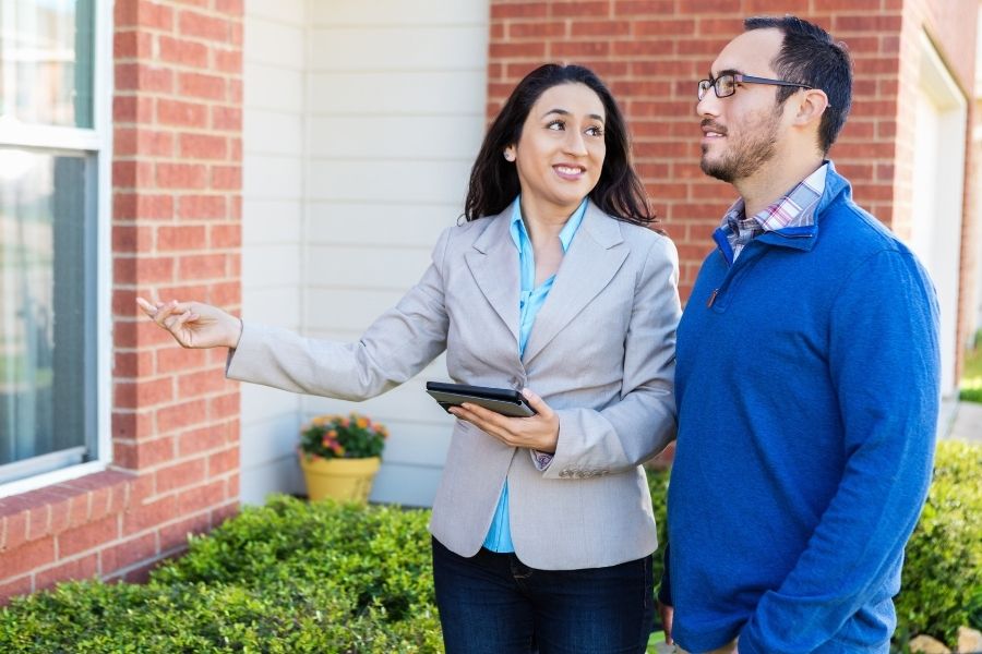 real estate agent and man looking at outside of brick home