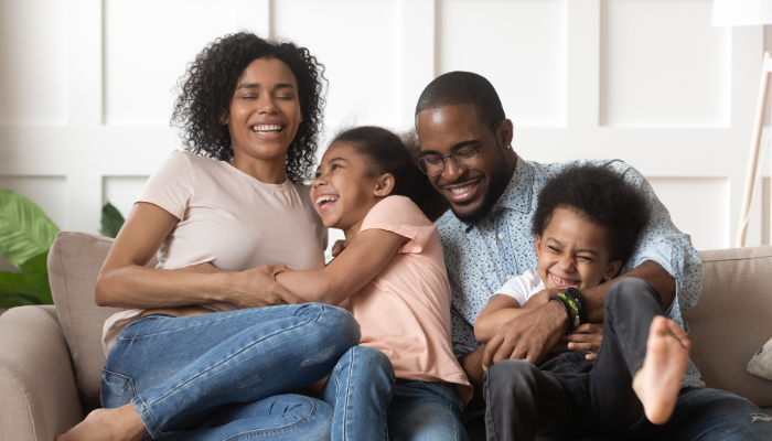 Playful family of four sitting on couch. 