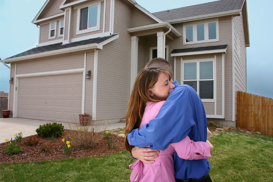 couple hugging in front of new home