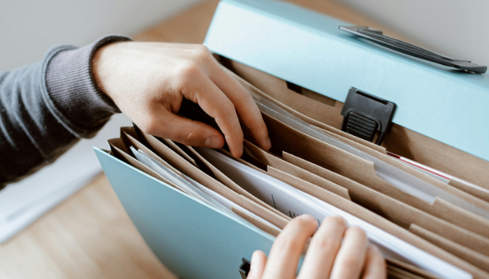 Person wearing long sleeves thumbs through file box.