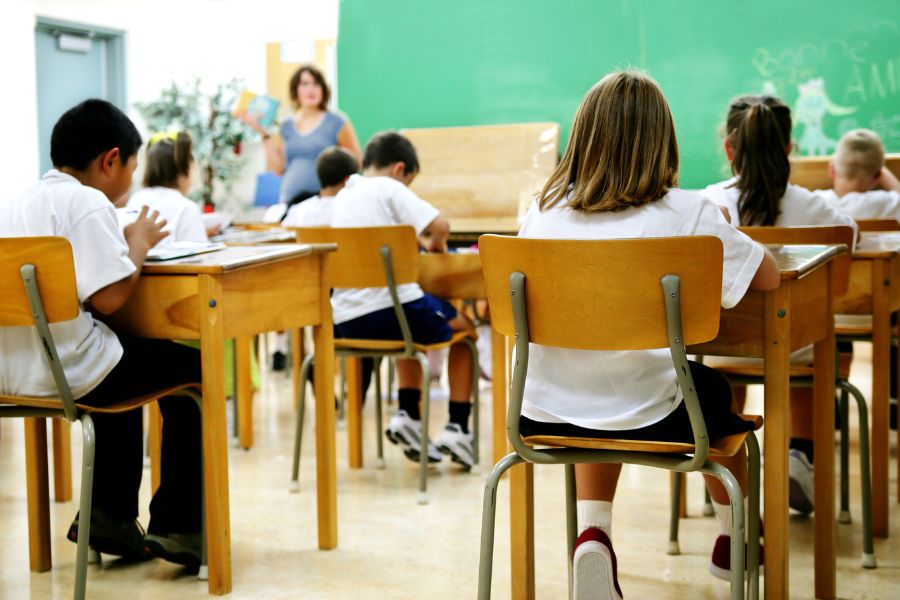 children in classroom sitting at desks with teacher