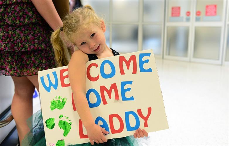 young girl holding welcome home daddy sign for deployment return