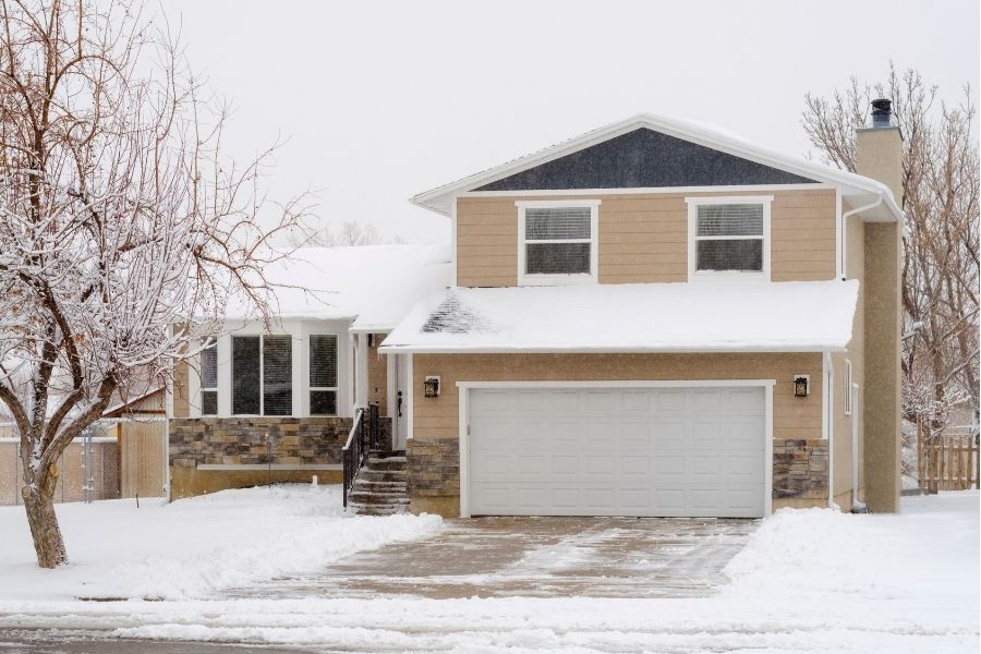 Eielson_AFB_housing tan home with white garage door, leafless trees and snow on ground and roof