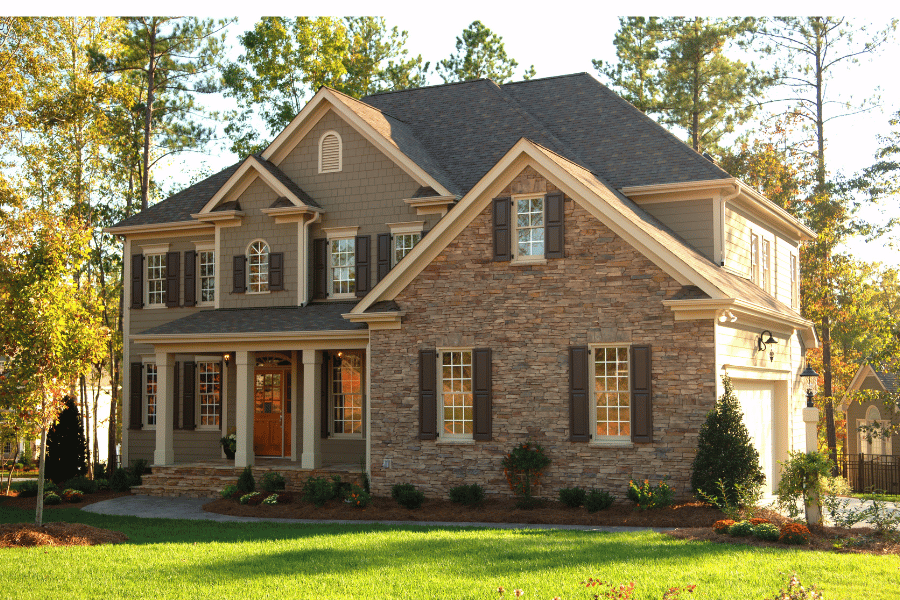 exterior of tan brick home surrounded by green grass and trees