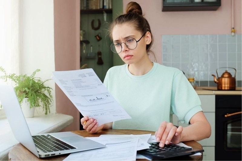 woman looking at calculator and financial paperwork