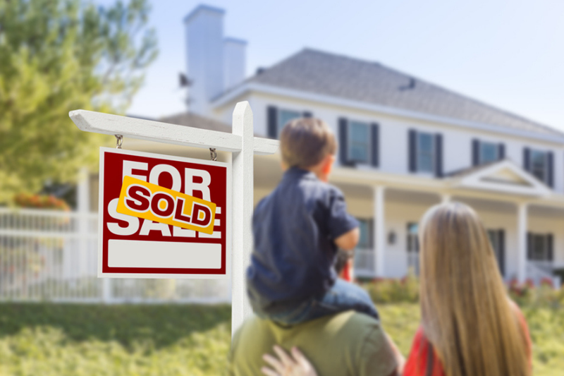 family with sold sign in front of home