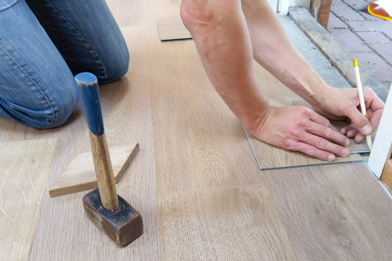 man measuring flooring for repairs