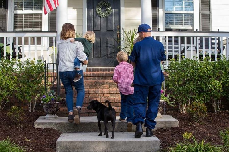 coast guard family walking up steps to new home