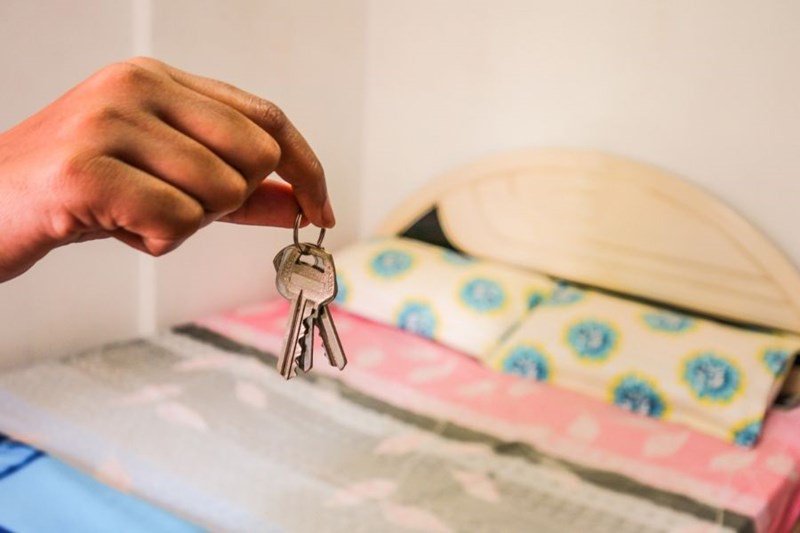 person holding keys in room for rent
