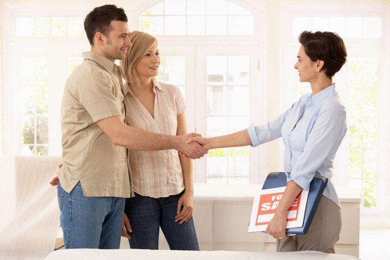 military family shaking hands with realtor as they buy home