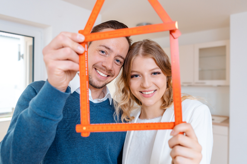couple holding miniature house frame