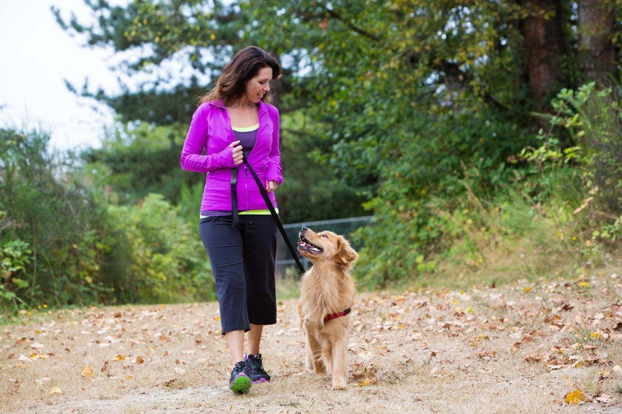 woman walking dog on nature trail