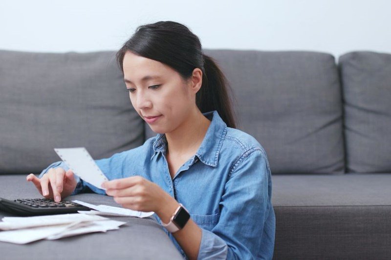 woman looking at receipts and calculator