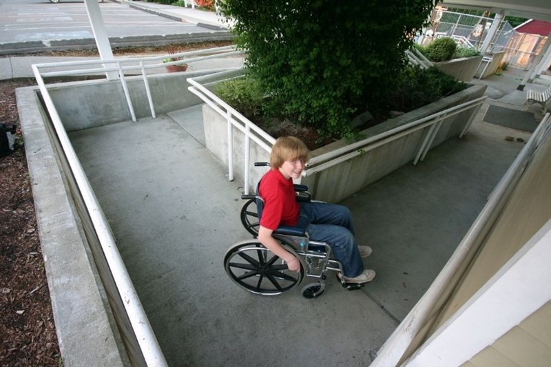 young man in wheelchair going up ramp