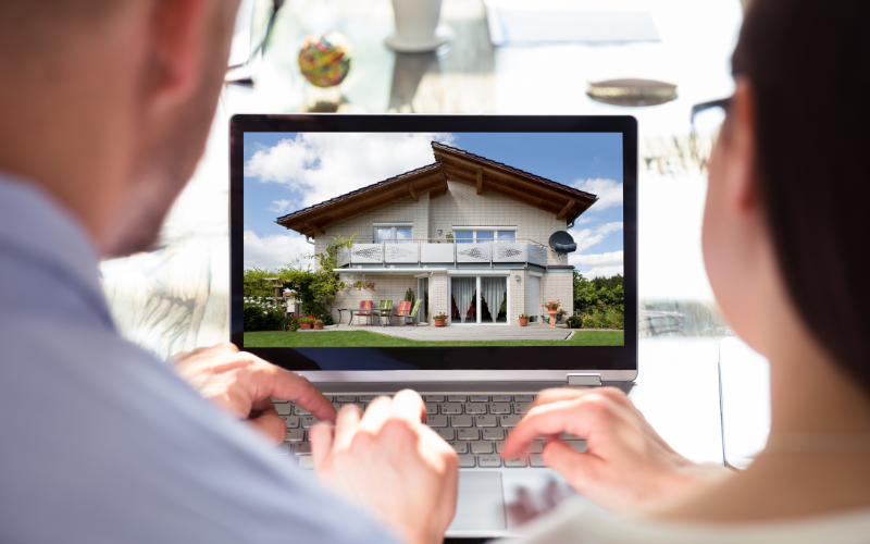 Man and woman sitting next to each other looking a real estate listing on computer.
