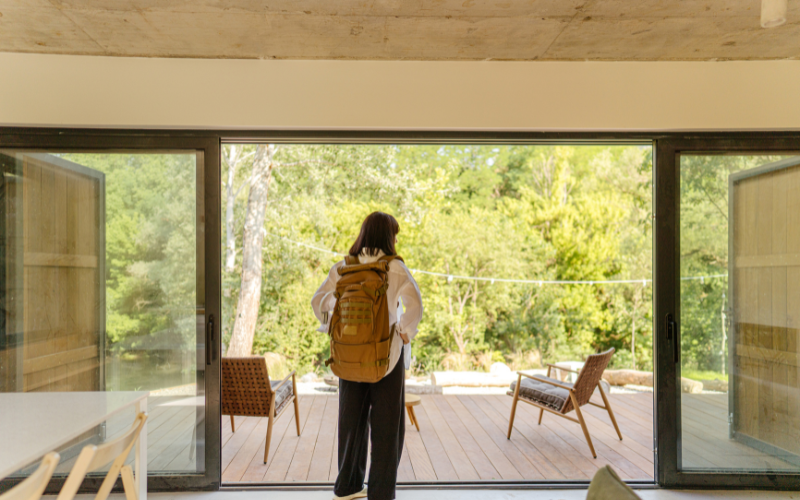 Woman standing in doorway of rental home wearing a backpack.
