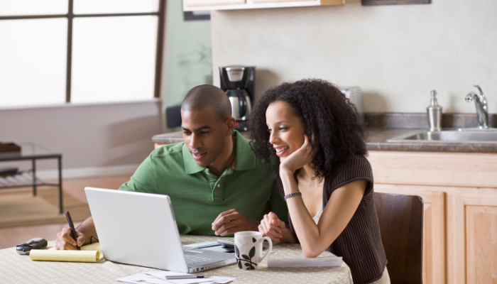 Couple sitting at table looking for a home to buy on the computer. 