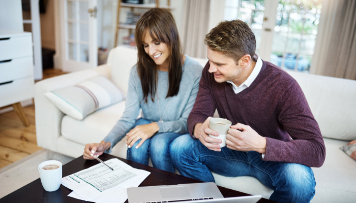 Couple sipping coffee as they discuss list of things needed to choose a home to buy.