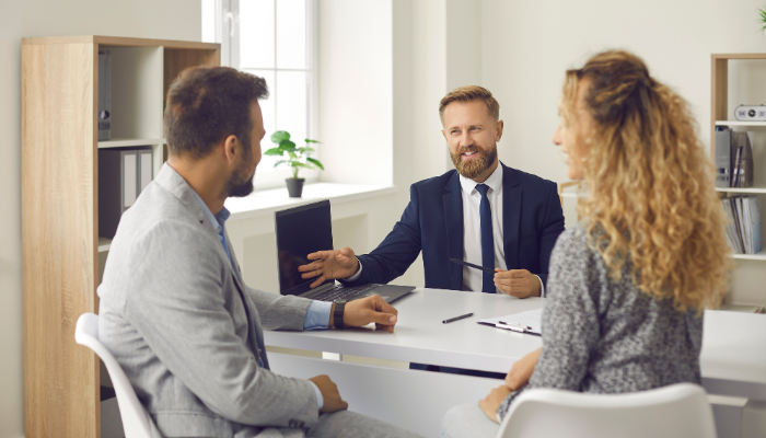 Couple meeting with real estate professional in blue suit.