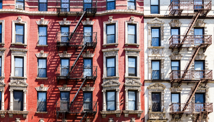View of red and white brick apartments buildings with fire escapes and windows in New York 