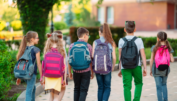 Line of kids walking toward school together.