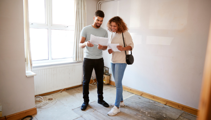 Couple standing in living room in home for sale looking over paperwork.