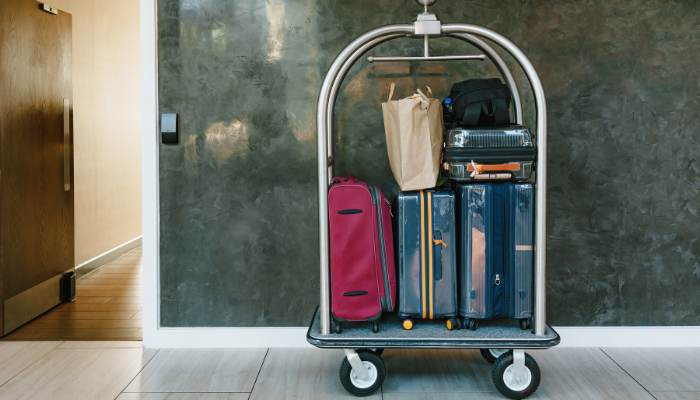 Luggage cart outside hotel room with brown bags and stacked hard cover suitcases