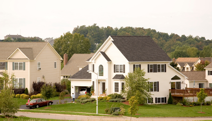 Large white home on lot in neighborhood with green grass