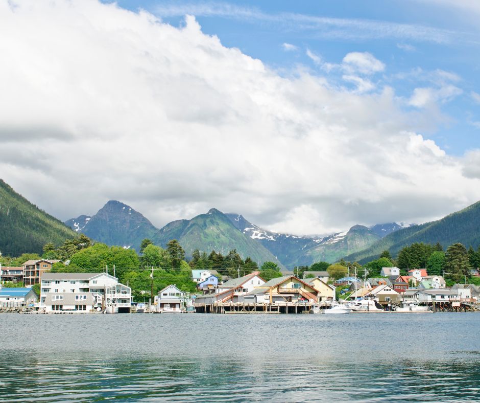 wide angle shot of Sitka, Alaska, homes near the water with mountains and blue sky in background