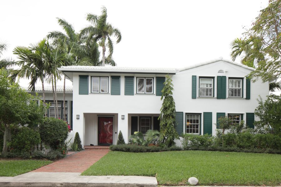 home near US_Southern_Command white home with green shutters, palm trees, green lawn in Florida