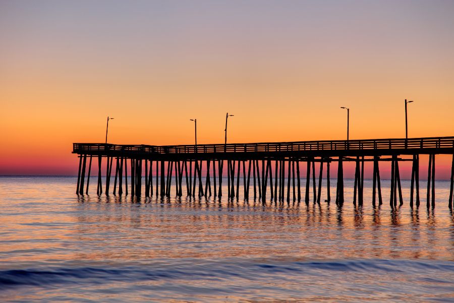 Virginia_beach_fishing_pier_at sunrise. Water and orange/yellow/blue sky