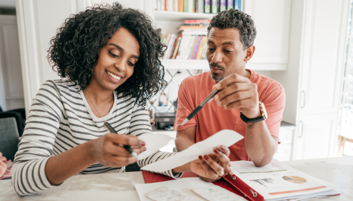 Couple looking at papers together using pen to point to notes.