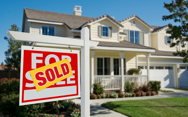 Light yellow home with white siding and a For Sale sign in the yard marked Sold