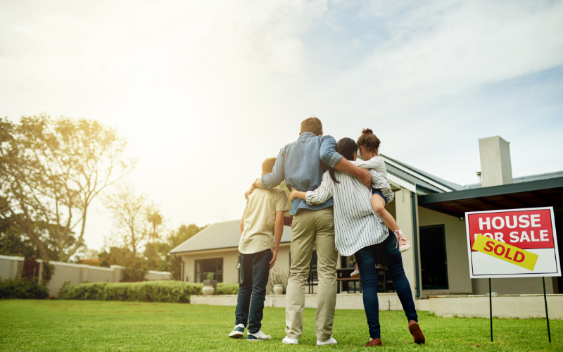 _family looking at house together with house for sale/sold sign