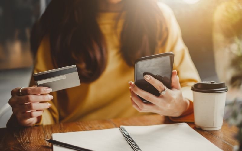 woman looking at credit card and phone to learn how to raise credit score